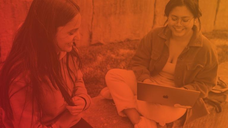 two girls on laptops sitting in grass with a red overlay