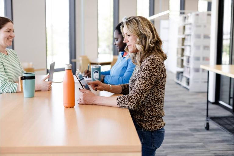 Older women is sitting at the library table on tablet